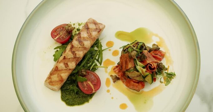 Concept of healthy food and of freshly salmon. Close up. Top View. Grilled fish, grilled salmon steak, aromatic spices and vegetables on white plate. Grilled salmon fish with various vegetables.