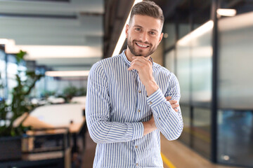 Portrait of happy businessman with arms crossed standing in office. - 779506630