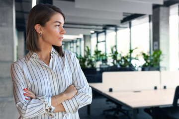 Attractive business woman in smart casual wear looking away while standing in the office
