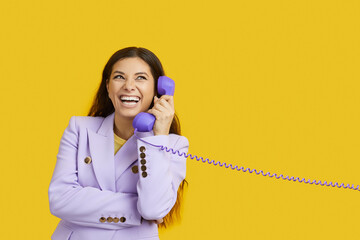 Beautiful emotional woman talking on landline phone isolated on vivid yellow background. Stylish...