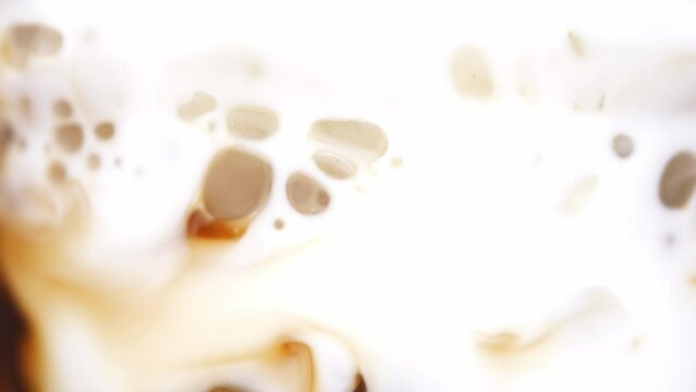 Close-up of a freshly brewed cup of coffee brown liquid inside mixed milk, Concept coffee art.
