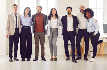 Obraz premium Business portrait, successful group of businesspeople in modern office looking at camera. Happy diverse multiethnic businessmen, satisfied businesswomen standing as team share unity success, smiling