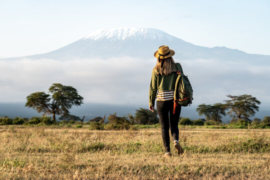 young beautiful girl walks through the savannah against the backdrop of Mount Kilimanjaro during a walking safari, travel concept, peaceful relaxing moment. happy earth day
