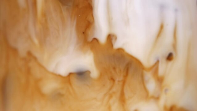 Close-up of a freshly brewed cup of coffee brown liquid inside mixed milk, Concept coffee art.

