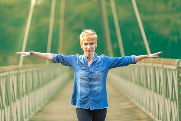 Arms wide, joyful woman on scenic bridge