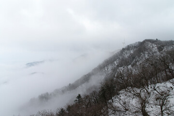 View of the wind turbine in the fog and snow on the winter mountain