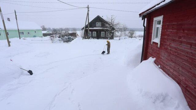 Using snow shovel to clear snow near rural home.