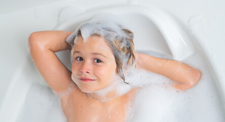 Kid having fun in the bath with bubbles. Happy child enjoying bath time. Little boy smiling in the bath with soap foam. Bath tub with soap bubble. Child bathes in a bathtub with foam.