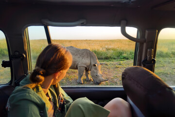 A Caucasian girl looks at animals in the savannah. The concept of travel and adventure in the wild. Young woman discover african nature by car with an open window. Tanzania safari
