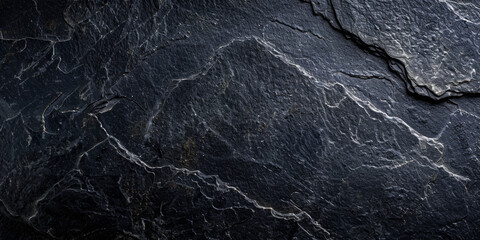 A black rock with a rough texture. The rock is large and has a jagged edge. The image has a moody and mysterious feel to it - obrazy, fototapety, plakaty