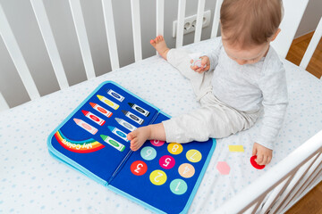 Baby happily plays with felt board in crib