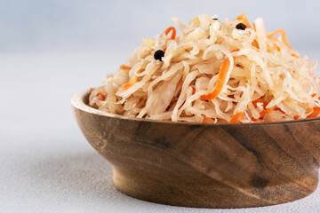 Sauerkraut with carrots and pepper in wooden bowl.