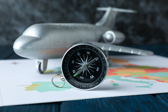 A compass on a table with an airplane.