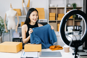 Fashion blogger concept, Young Asian women selling clothes on video streaming.Startup small business SME, using smartphone or tablet taking receive and checking