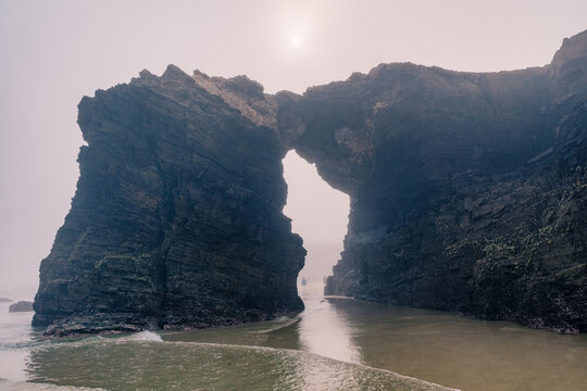 Cathedrals beach in Galicia, Spainn. Foggy landscape with Playa de Las Catedrales Catedrais beach in Ribadeo, Lugo on Santabrian coast. Natural archs of Cathedrals beach. Moody rock formations