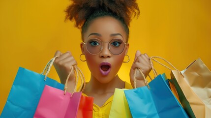 Stylish chic African American woman with colorful shopping bags in surprise sale concept isolated on yellow banner background. - obrazy, fototapety, plakaty