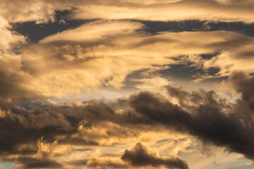 Scenic shot of golden and dark clouds in the sky at sunset