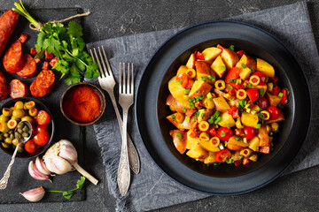 spanish potato salad with chorizo in black bowl