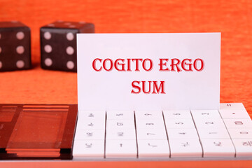 The words Cogito Ergo Sum or I think Therefore I Am on a white business card on a calculator on an...
