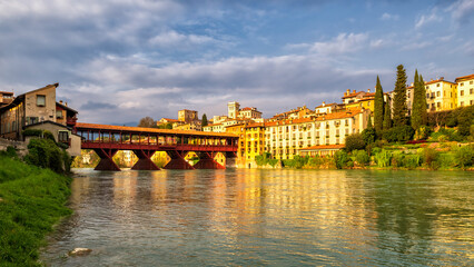 Antique wooden covered red bridge over a river at sunset time. Ponte Vecchio or Ponte degli Alpini...