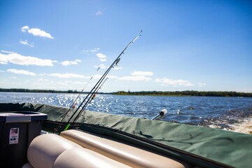 Pontoon boat with fishing poles on a lake on a sunny day