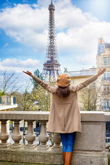 A happy woman with a french beret hat looks at the beautiful cityscape of Paris, France, with Eiffel Tower - 779544274
