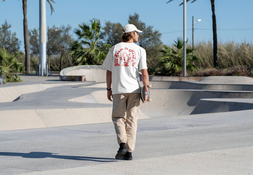 Mockup of skater wearing customizable t-shirt carrying skateboard