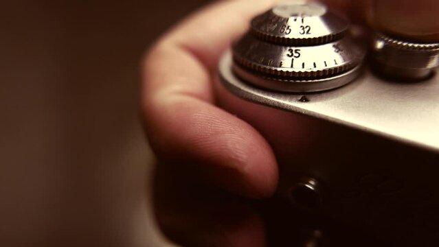 Closeup of an old film camera in hands to check it, with sepia color stylization