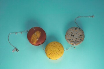 close-up of an elegant silver necklace with a multicolor gemstones between three multicolor macaronies cakes on an azure background