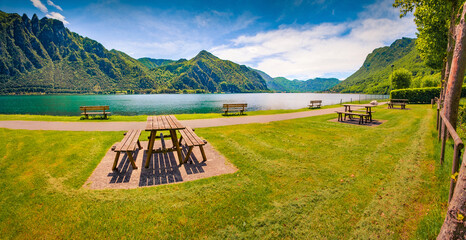 Old wooden table and sits on the shore of Idro lake. Attractive spring scene of Anfo comune in the Brescia region, northern Italy, Europe. Beauty of countryside concept background. - 779556883