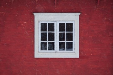 Closeup of a white framed window on red wooden wall.