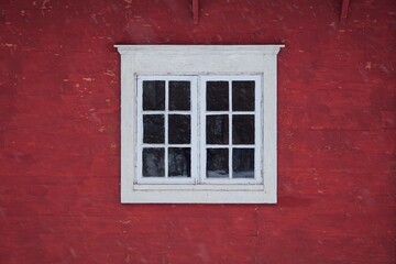 Obraz premium Closeup of a white framed window on red wooden wall.