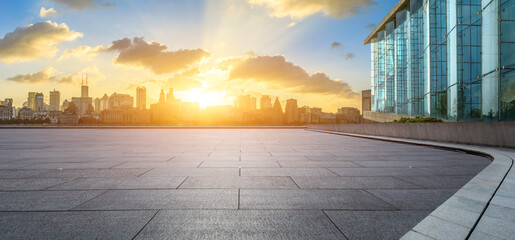 Empty square floor and glass wall with modern city buildings at sunset in Shanghai. Panoramic view.