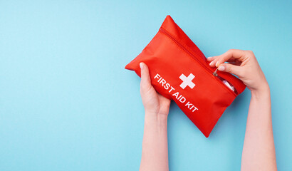 Close-up of a woman's hands holding a fully-equipped first aid kit, ready for providing immediate medical assistance in case of emergencies. Concept of preparedness, healthcare, and safety.