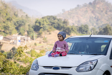 innocent child sitting at car bonnet cute facial expression at outdoors at morning from flat angle