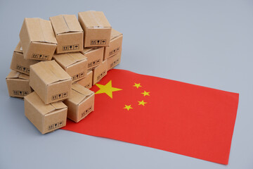 Goods made in China concept. Chinese flag and many carton boxes on grey background.	