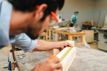 Carpenter working with electric planer on wooden plank in workshop. Craftsman makes own successful...