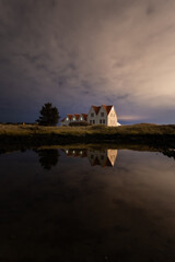 Reflejo nocturno de un cielo con nubes sobre un lago en calma de casas tradicionales islandesas
