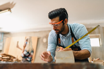 Carpenter working with electric planer on wooden plank in workshop. Craftsman makes own successful small business, man using tool in carpenter's shop to making a furniture from wood - obrazy, fototapety, plakaty