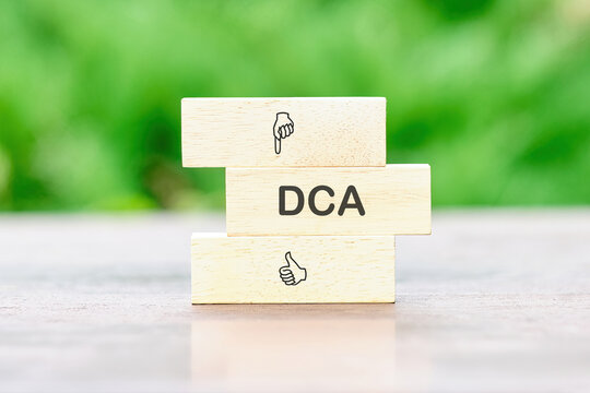 Business concept. Dollar cost averaging investment strategy. DCA on a wooden bar on a table on a green background
