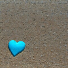 a blue heart on the beach with water and pebbles as backdrop