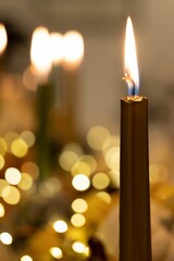 Vertical shot of a lit candle with bokeh lights in the blurred background for Thanksgiving dinner