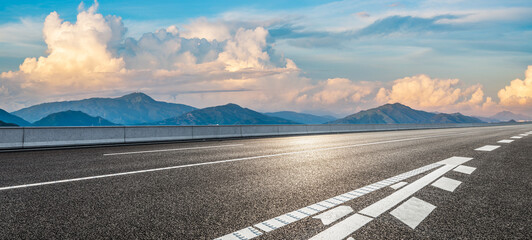 Asphalt highway road and mountains with sky clouds at dusk. Panoramic view.