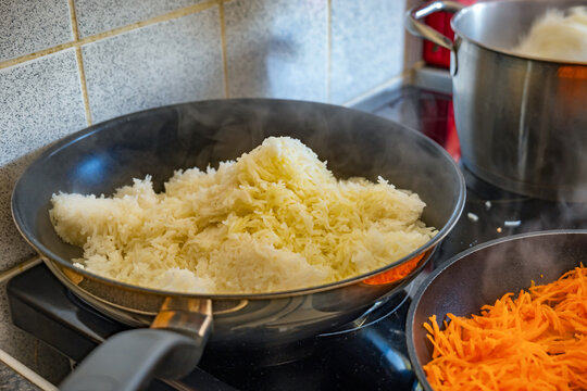 Cooking fried rice in a frying pan on a kitchen stove