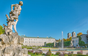 Salzburg, Austria -  October 6, 2022: The  Mirabell palace and garden's fountain and statue  with the St Andrew bell tower in the background