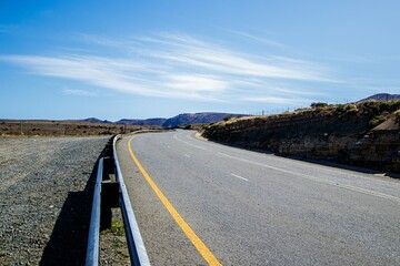 Scenic landscape of a countryside road with mountain peaks in the background during daytime