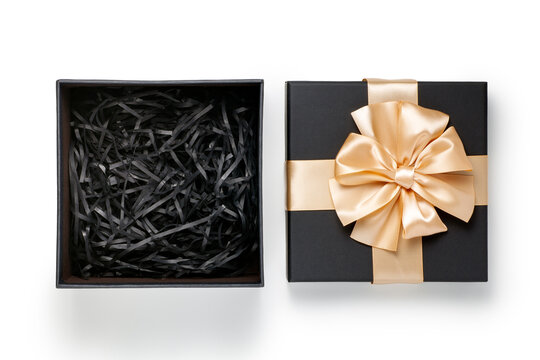 Black gift box with champagne gold ribbon bow on white background. top view