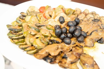 Closeup shot of the freshly cooked sliced zucchini and eggplant in sauce with black olives