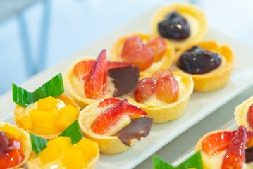 Closeup shot of tasty and sweet tartlets with fruits put on the white plate - obrazy, fototapety, plakaty