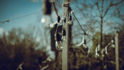 Wooden poles decorated with lights - obrazy, fototapety, plakaty